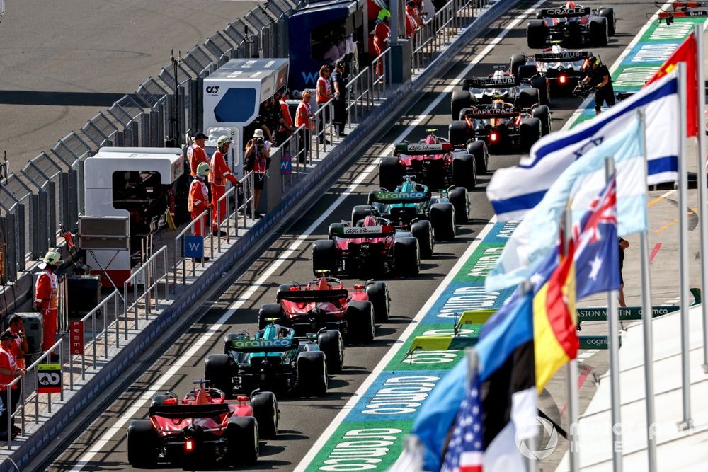 Sergio Perez, Red Bull Racing RB19, leads Yuki Tsunoda, AlphaTauri AT04, Daniel Ricciardo, AlphaTauri AT04, Lando Norris, McLaren MCL60, Zhou Guanyu, Alfa Romeo C43, Lance Stroll, Aston Martin AMR23, Valtteri Bottas, Alfa Romeo C43, and others out of the pit lane